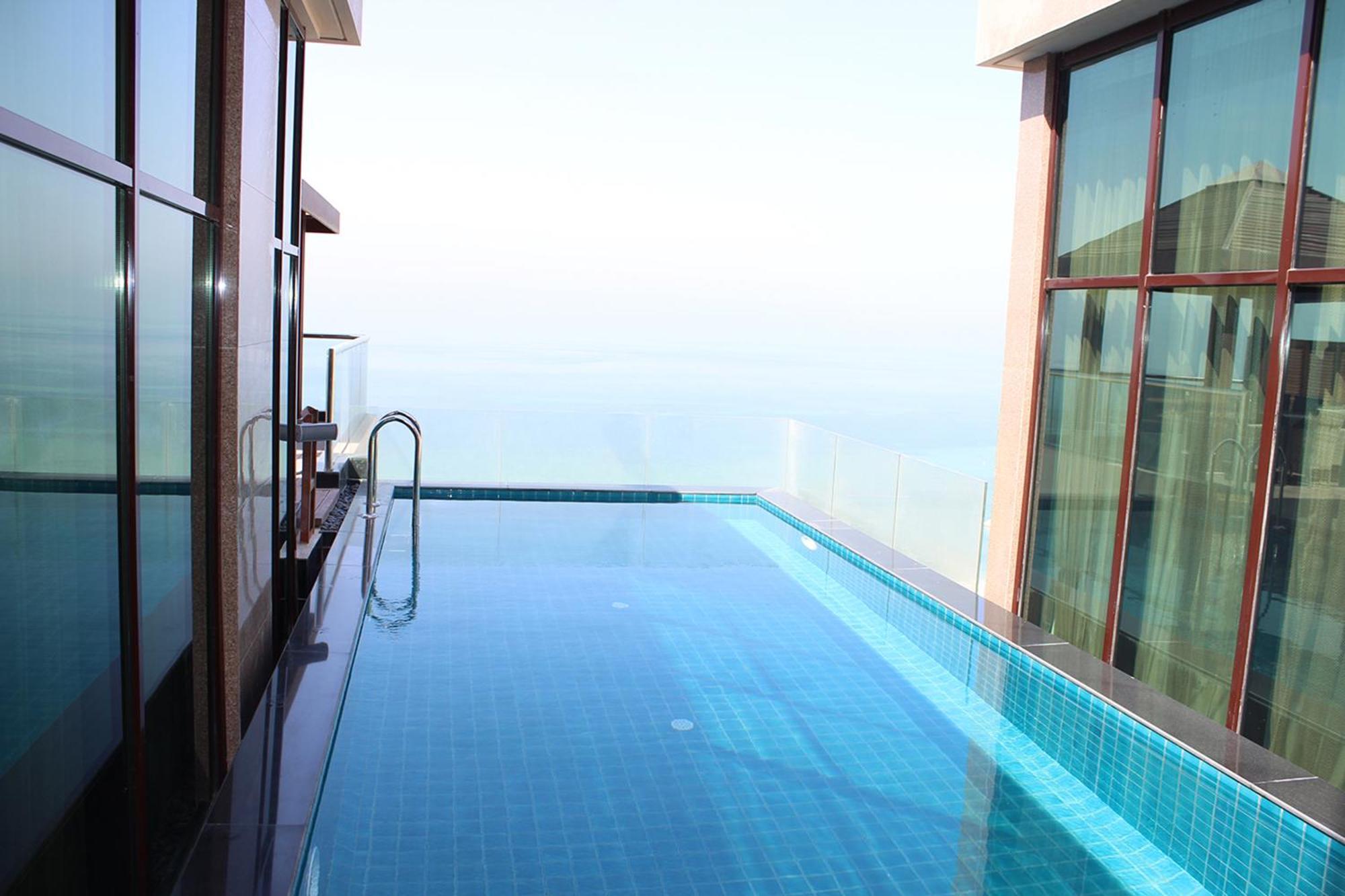 Lagoona Beach Luxury Resort And Spa Manama Exterior foto The photo shows an infinity pool situated on a balcony or rooftop, with a clear view extending to the horizon. The pool has a sleek design with blue tiles, and it appears to be reflecting the sky. There is a ladder on one side for access into the poo