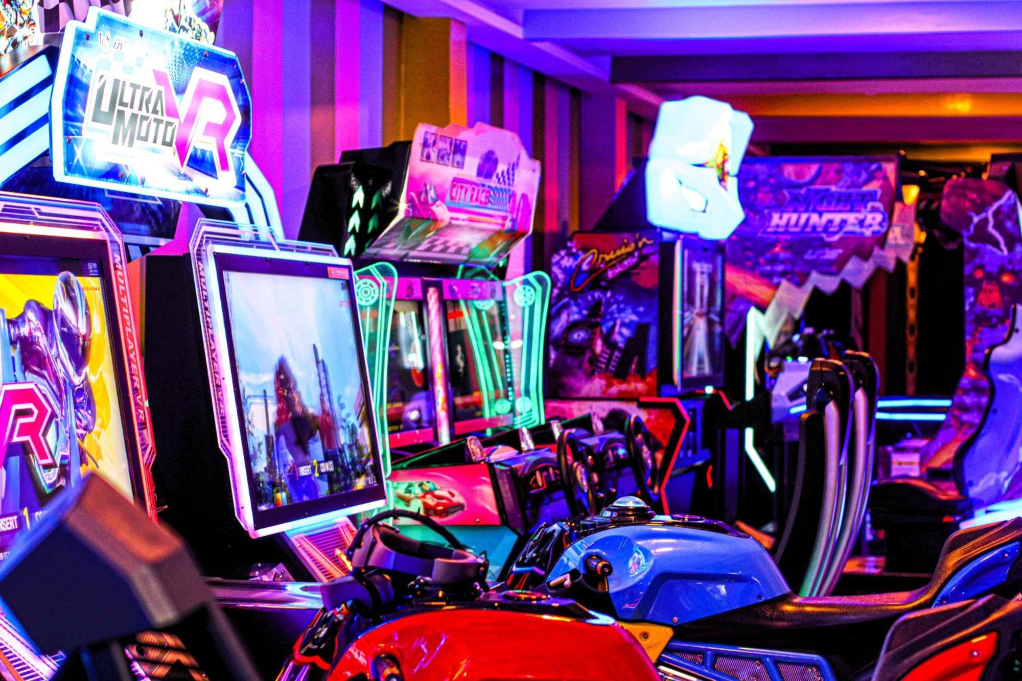 Lagoona Beach Luxury Resort And Spa Manama Exterior foto The photo shows a vibrant arcade scene featuring various arcade gaming machines. The machines are lined up, showcasing colorful screens and bright, neon lights, creating an energetic atmosphere. Some machines appear to be racing games, as indicated b