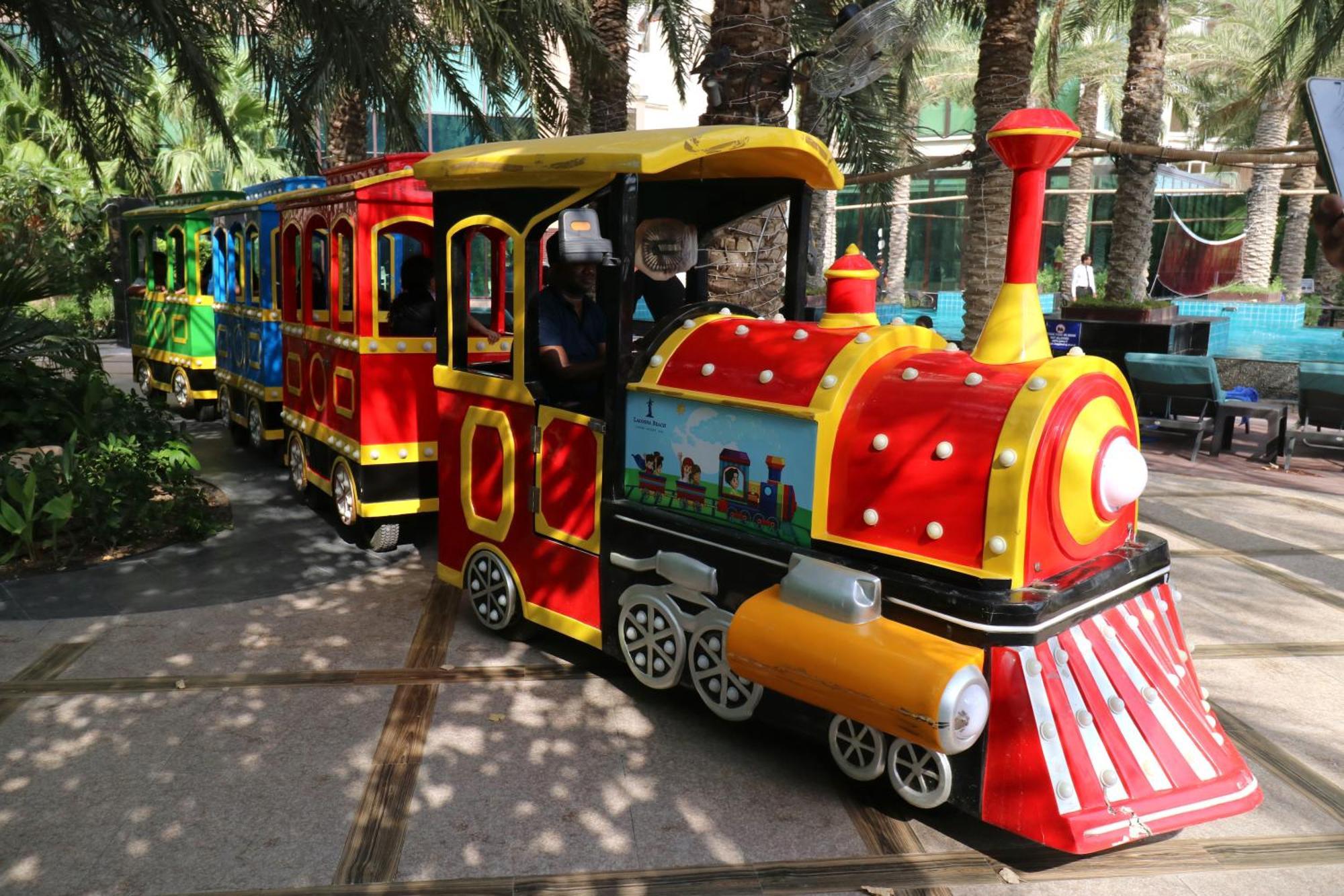 Lagoona Beach Luxury Resort And Spa Manama Exterior foto The photo shows a colorful miniature train. It features a vibrant design with bright red, yellow, and blue colors. The front of the train resembles a classic steam engine, complete with a prominent smokestack. The train is designed to resemble a fun 