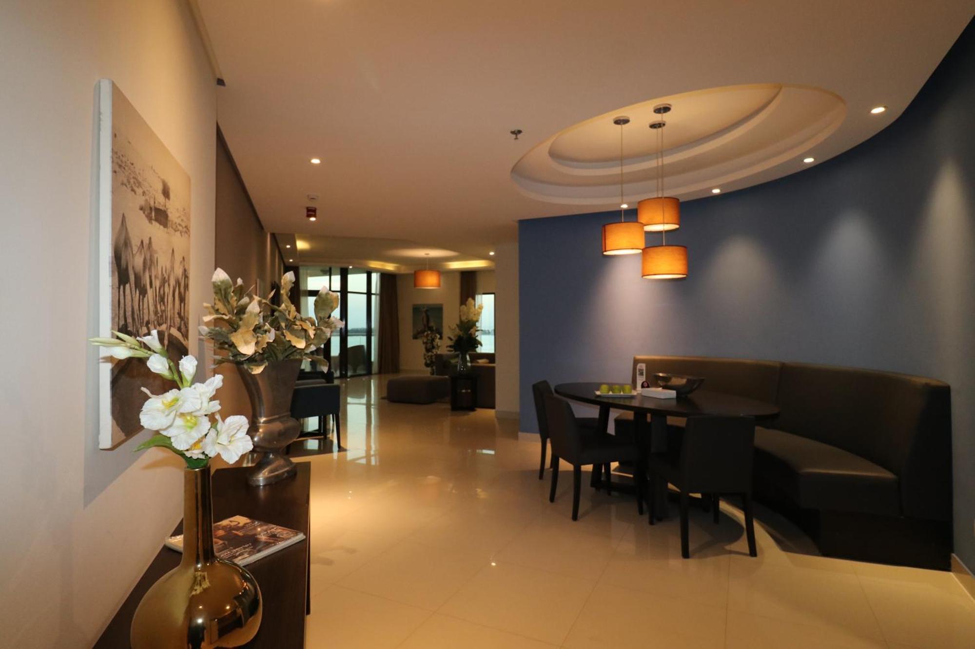 Lagoona Beach Luxury Resort And Spa Manama Exterior foto The photo showcases an interior space, likely a modern lounge or reception area. It features a combination of soft lighting, neutral-colored walls, and decorative elements. There are elegant light fixtures hanging from the ceiling, and a curved blue 