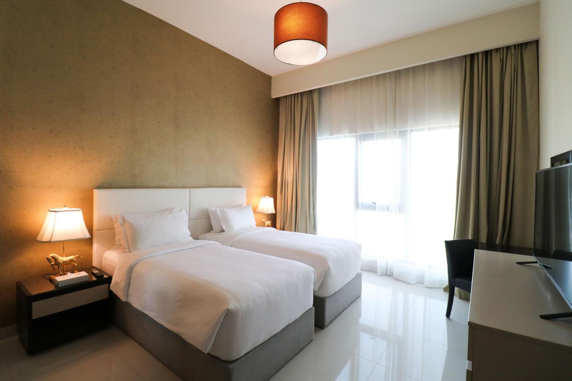 Lagoona Beach Luxury Resort And Spa Manama Exterior foto The photo shows a hotel room featuring two single beds with white bedding. The walls have a neutral tone, and there's a large window covered by light, sheer curtains allowing natural light to enter. On either side of the beds, there are bedside table